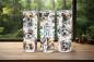 Preview: Drei Thermobecher mit dem Design „Life is Better with Dogs“ stehen auf einem Holztisch vor einem Fenster mit Blick auf einen grünen Wald. Jeder Becher zeigt ein fröhliches Hundemotiv, inklusive verschiedener Rassen und farbenfroher Details wie Schleifen u